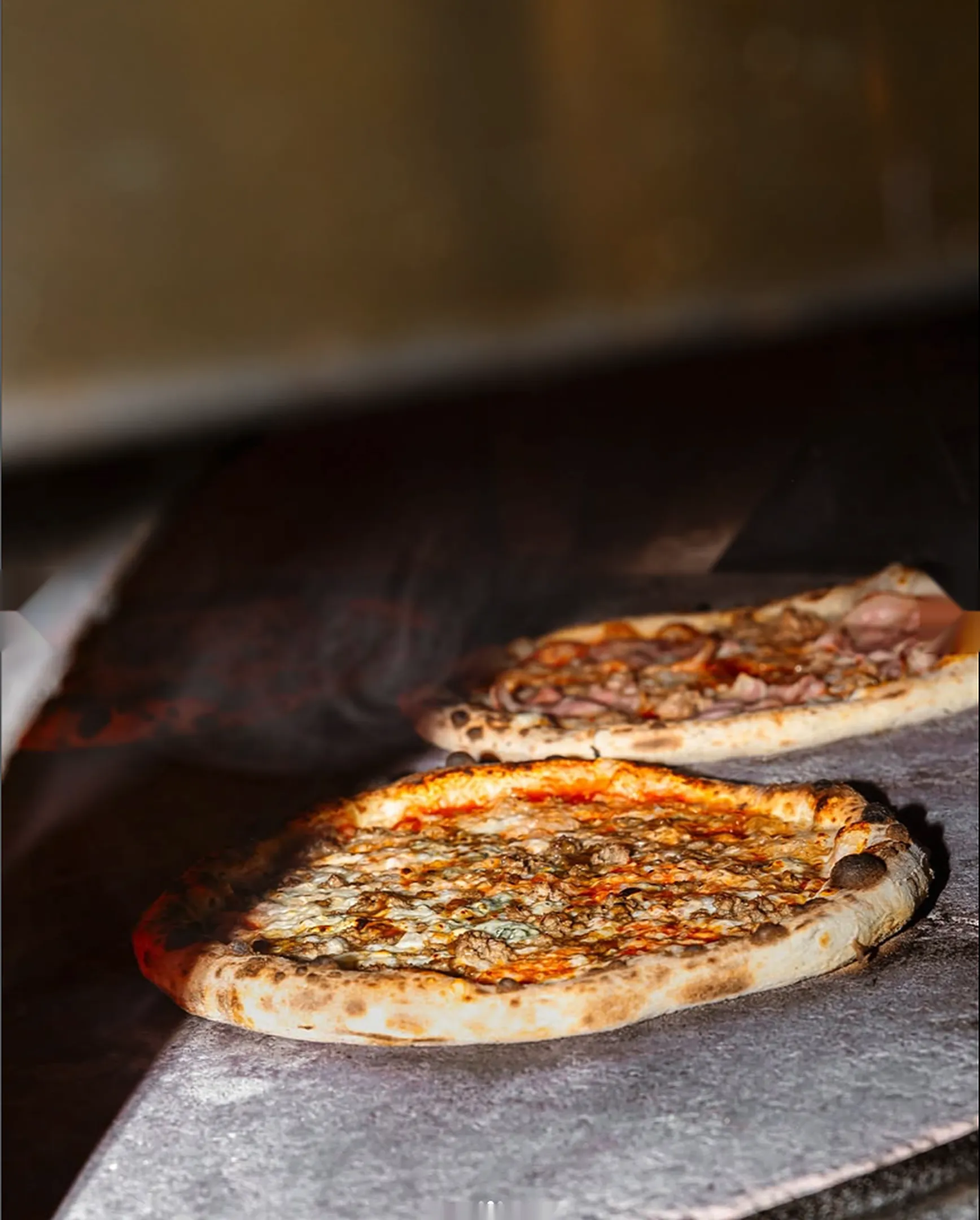 Dos pizzas recién salidas del horno de leña