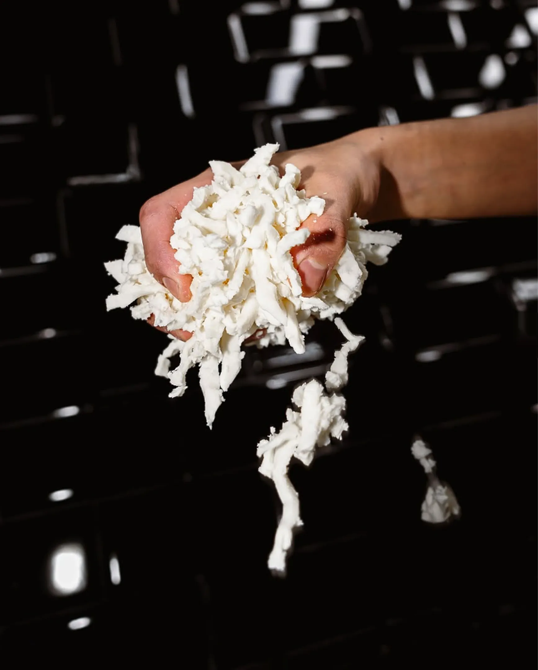 Mano sosteniendo mozzarella fresca deshilachada